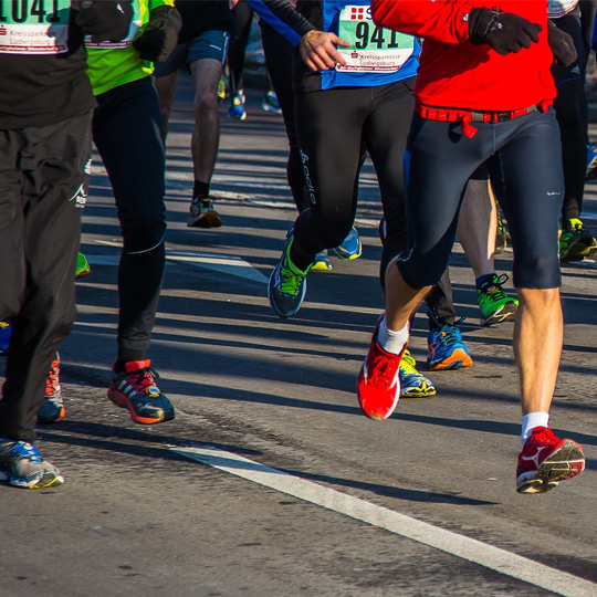 Photo of group of people running cropped from the waist down